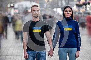 The young man and woman stand in the middle of the street and hold hands.