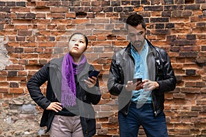 Young man and woman stand nearby looking at their smartphones, girl suddenly saw the sky