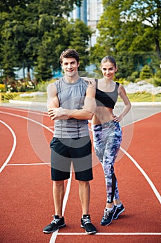 Young man and woman standing on athletics race track