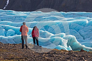 Young man and woman standing before of beautiful evening scenery of Skaftafell glacier Vatnajokull National Park in Iceland