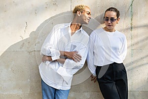 Trendy Young Couple in Casual Chic Attire Leaning Against Wall photo