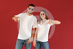Young man and woman in stylish t-shirts on color background photo