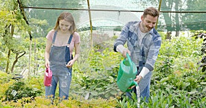 Young man and woman taking care of plants and watering with pot