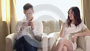 Young man and woman with telephones in armchairs