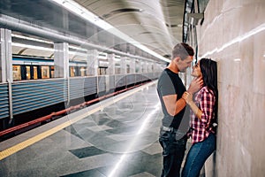 Young man and woman use underground. Couple in subway. Cheerful paasionate people lean to wall. kissing time. Guy hold