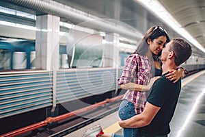 Young man and woman use underground. Couple in subway. Love story. Young man hold woman in hands and kiss. Love at first