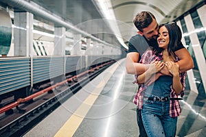 Young man and woman use underground. Couple in subway. He stand behind her and embrace. Kissing scene. Cheerful young