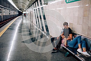 Young man and woman use underground. Couple in subway. Young woman lying on guy`s nap. He look at her and embrace. Love