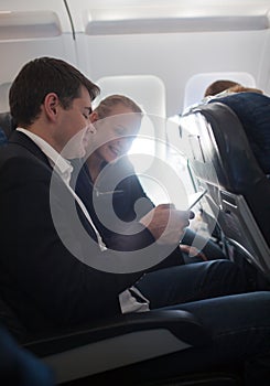 Young man and woman using cell phone in plane