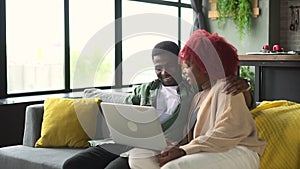 Young man, woman using laptop and cuddling while sitting on sofa in home room spbd.