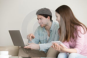 Young man and woman using laptop, tablet, talking, shopping onli