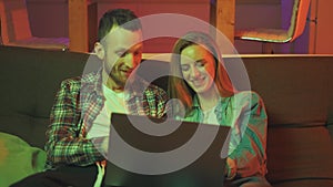 A young man and woman are using laptop together, looking at screen, shopping or chatting online, using internet banking