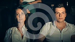 Young man and woman watch movie, embrace in cinema theater