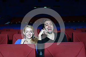Young man and woman watch movie and laugh in movie theater