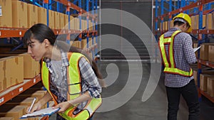 Young man and woman worker check stock and inspection with document on clipboard in the warehouse at factory.