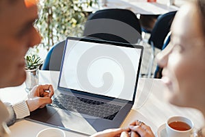 Young man and woman working in front of the laptop with blank white screen