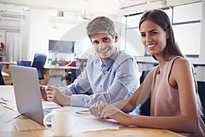 Young man and woman working in office smiling to camera