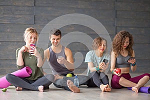 Young man and women resting on floor after successful exercising in gym.