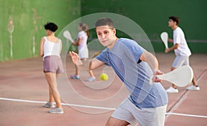 Young man with wooden paleta playing pelota goma on outdoor court photo