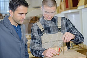 Young man in woodworks training with professional teacher