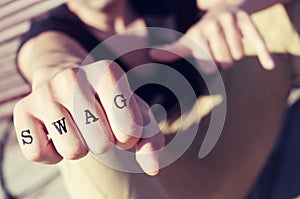 Young man with the word swag tattooed in his fist, with a filter photo