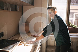 Young man work in his workshop. Handsome guy make an element of decor