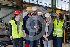 Young man worker with Down syndrome with manager and other collegues working in industrial factory, social integration