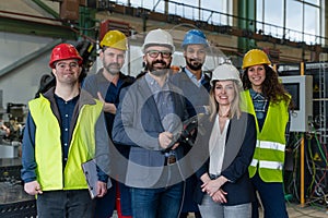 Young man worker with Down syndrome with manager and other collegues working in industrial factory, social integration