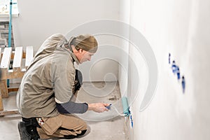 Young man, worker glueing wallpapers on concrete wall. Repair the apartment. Home renovation concept. White Wallpaper