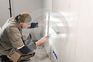 Young man, worker glueing wallpapers on concrete wall. Repair the apartment. Home renovation concept. White Wallpaper