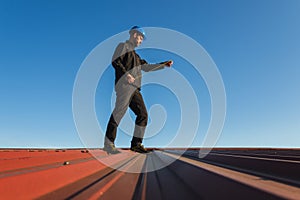 Young man worker in helmet holding meter tape on roof with blue sky. Roofer work background