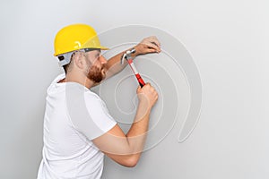 Young man worker is hitting the hammer to nail on the wall for construction or renovation.