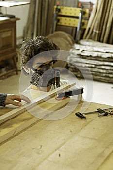 A young man working as carpenter in his wood workshop. Wood worker designing and handcrafting new house furniture using a piece of