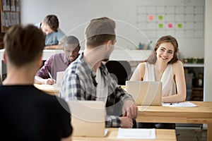 Young man working in co-working space talking to smiling woman