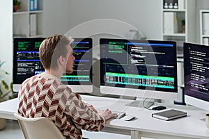 Young Man Working with Code on Multiple Computer Monitors