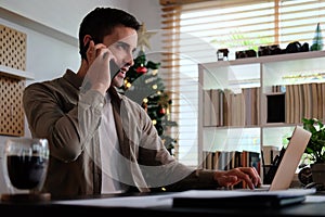 Young man working with computer laptop and talking on mobile phone