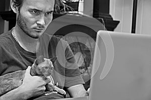 Young man working at computer with pet cat kitten