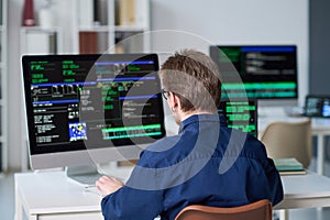 Young Man Working on Computer with Programming Code Displayed