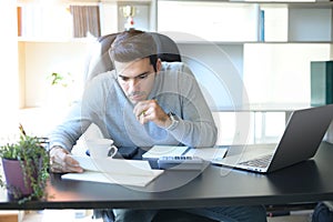 A young man working at a desk with a laptop.