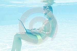 Young man working with his laptop underwater