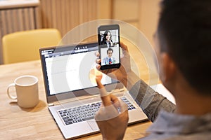 Young man working at home and using smart phone with video conference