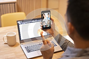 Young man working at home and using smart phone with video conference