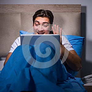 Young man working on laptop in bed