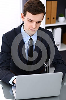 Young man working with laptop computer, man`s hands on notebook, business person at workplace