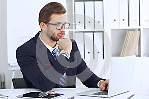 Young man working with laptop computer, man`s hands on notebook, business person at workplace