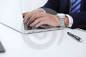 Young man working with laptop computer, man`s hands on notebook, business person at workplace