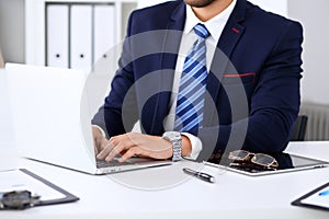 Young man working with laptop computer, man`s hands on notebook, business person at workplace