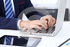 Young man working with laptop computer, man`s hands on notebook, business person at workplace