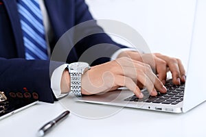 Young man working with laptop computer, man`s hands on notebook, business person at workplace