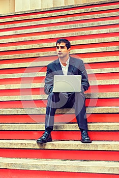 Young man working on laptop computer on stairs in New York City